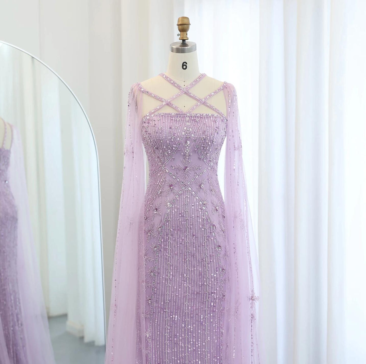 Lavender mermaid gown with criss-cross neckline, cape sleeves, and intricate crystal and sequin beadwork on tulle.