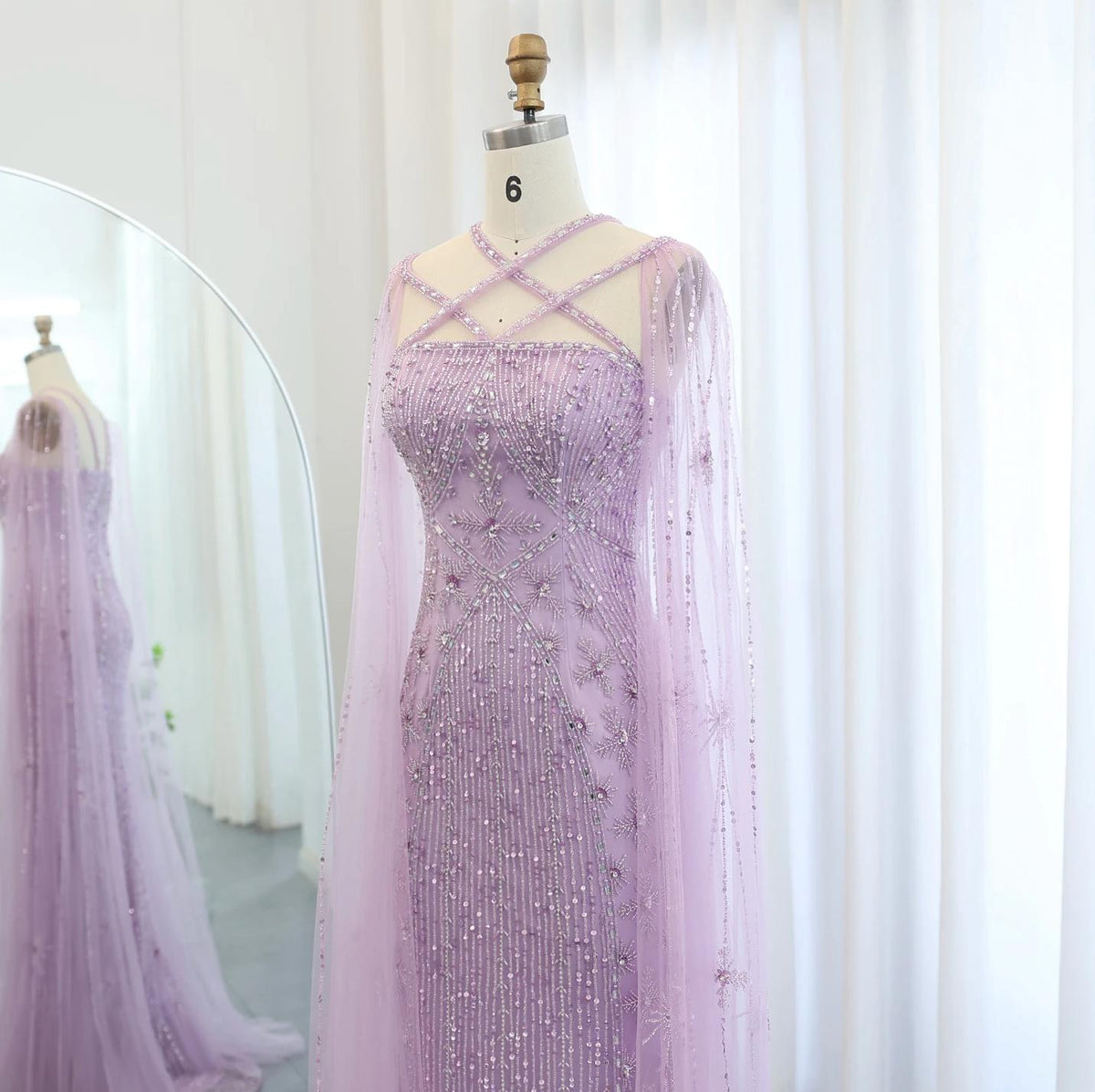 Lavender mermaid gown with criss-cross neckline, cape sleeves, and intricate crystal and sequin tulle detailing.