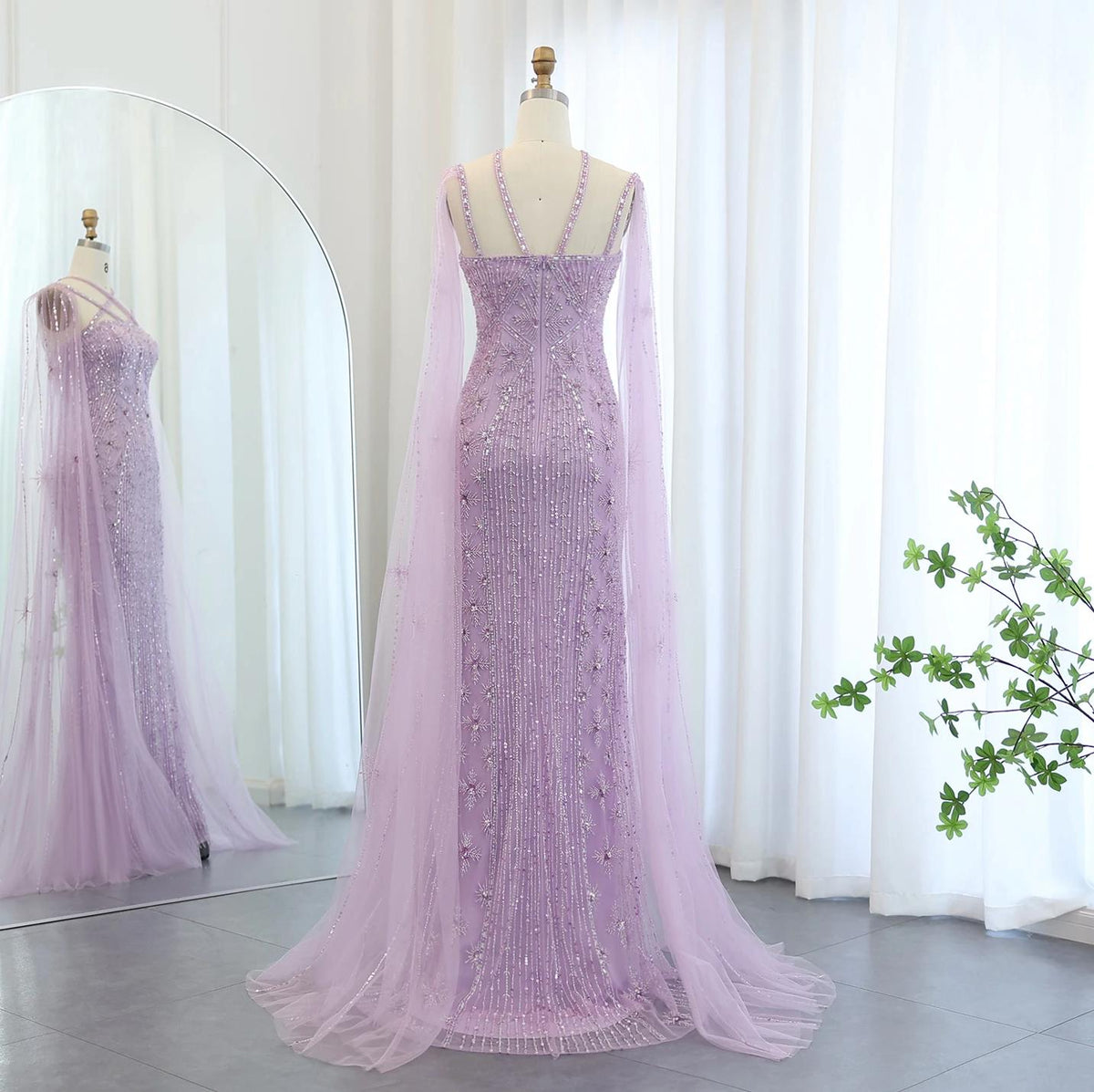 Lavender mermaid gown with cape sleeves, intricate beadwork, shimmering crystals, and sequin tulle on a mannequin.