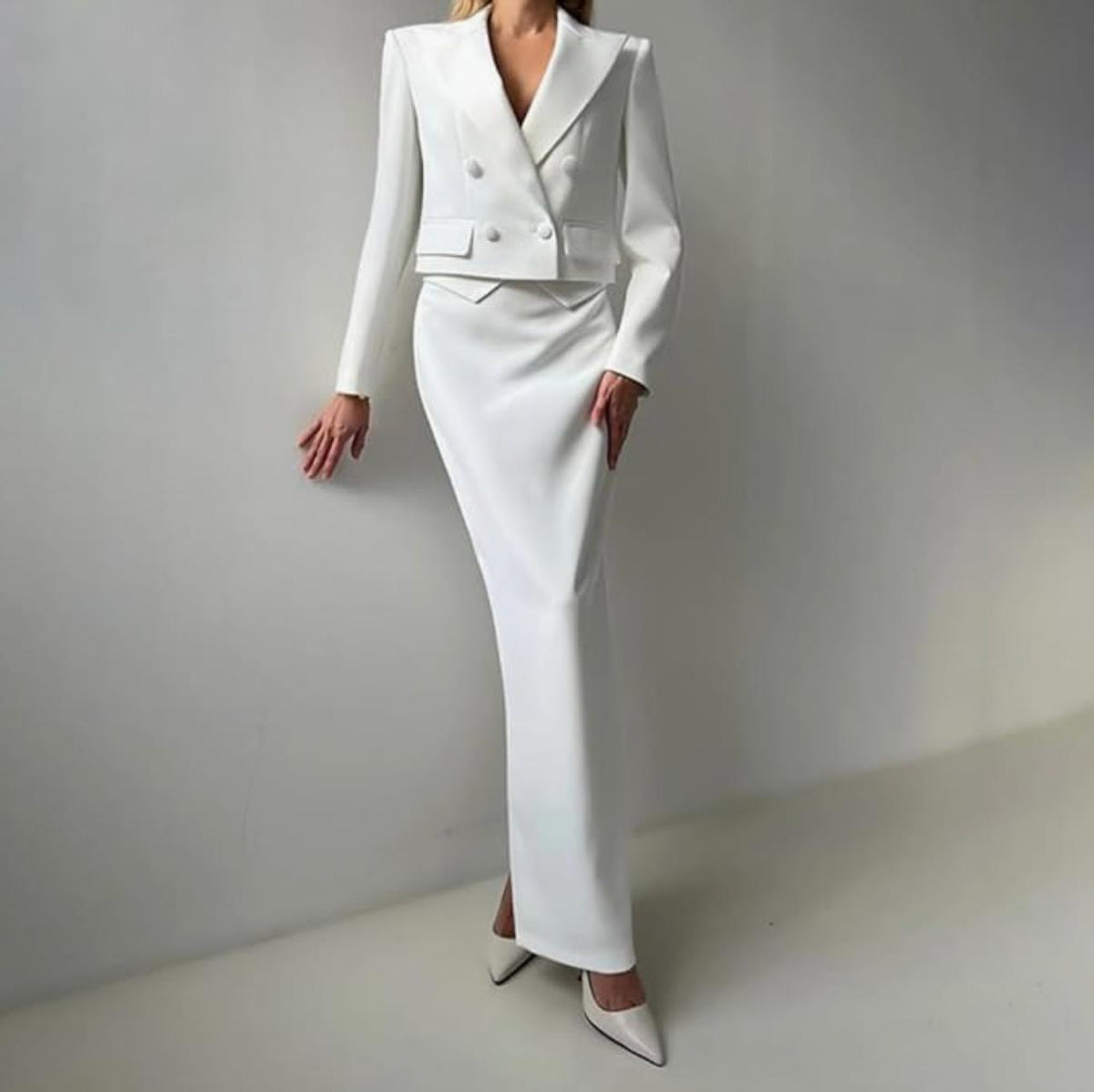 White double-breasted cropped blazer and matching floor-length maxi skirt in a tailored, slim-fit silhouette.