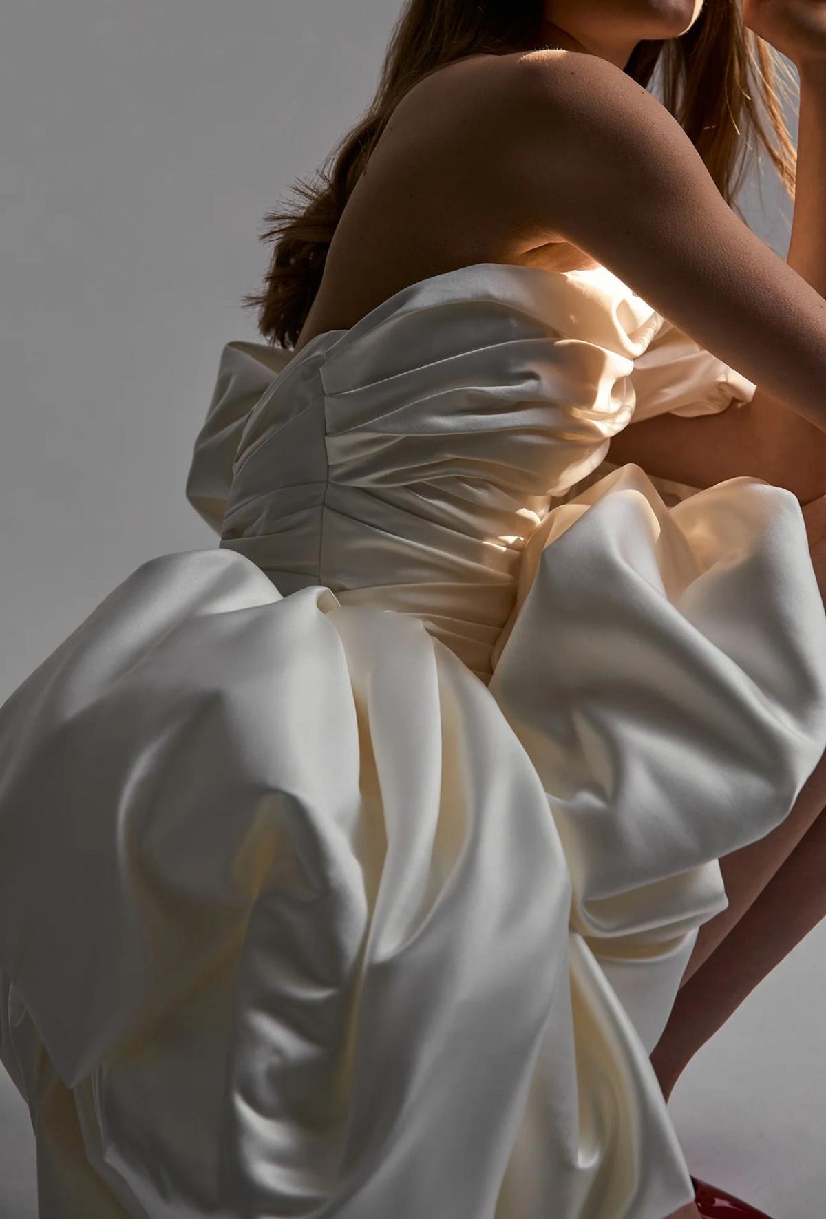 White strapless mini dress in ruched satin with a voluminous ruffled skirt and sweetheart neckline.