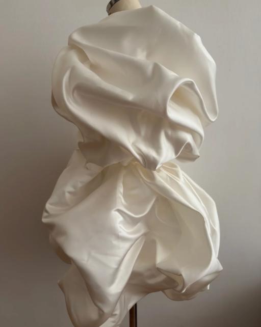 White strapless mini dress in ruched satin with a ruffled sweetheart neckline and elegant A-line silhouette.