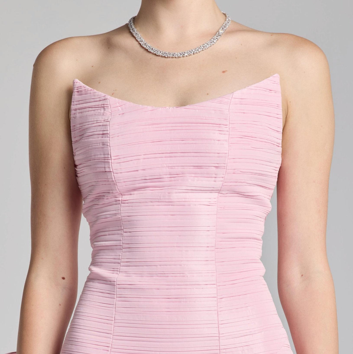 Strapless light pink satin Candelaria gown featuring a fitted bodice with horizontal pleated detailing.