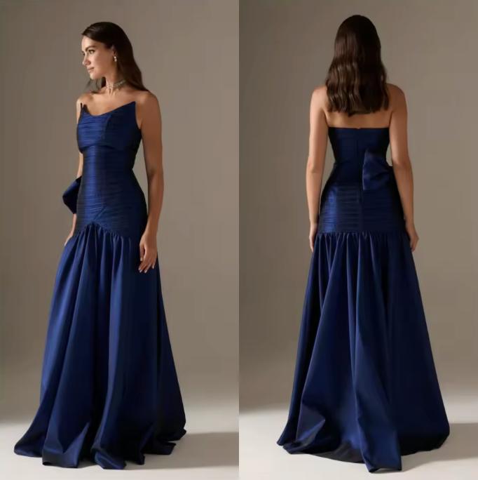 Strapless navy blue satin A-line gown with pleated bodice, floor-length skirt, and a dramatic bow on the back.