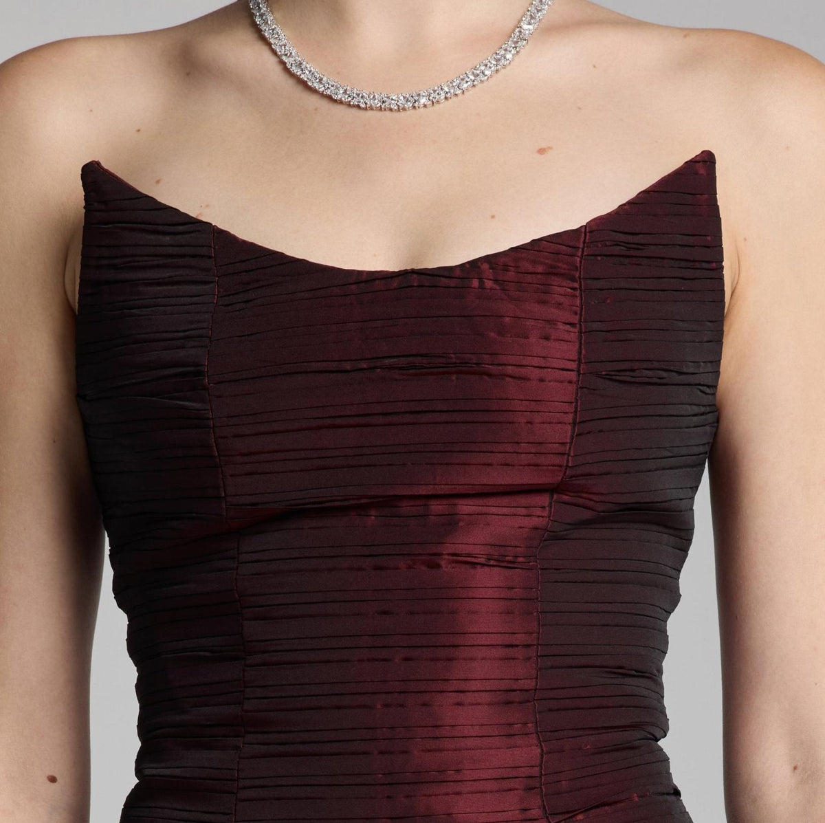 Strapless burgundy satin Candelaria gown featuring a pleated bodice and elegant sweetheart neckline.