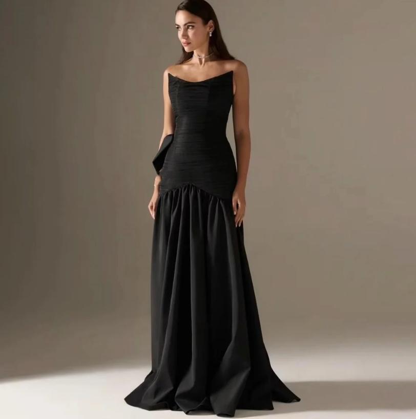 Elegant black strapless A-line satin gown with a pleated bodice and dramatic back bow detail for formal events.