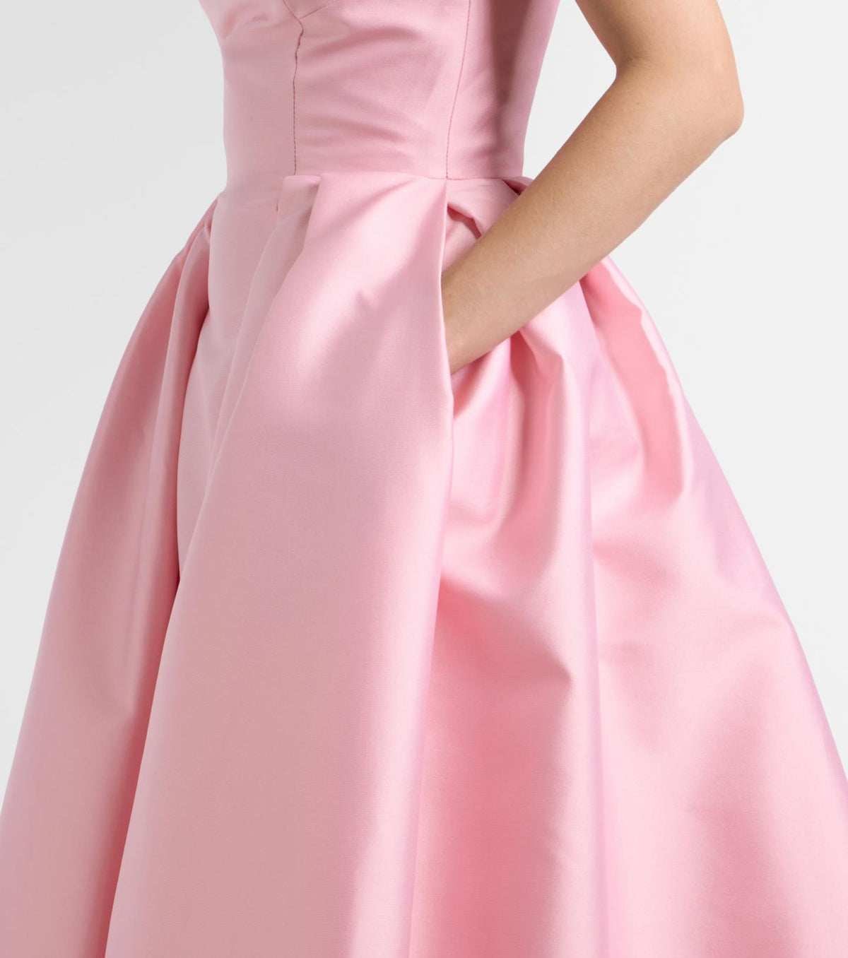 Pink satin Carnation gown with a structured bodice and a full, pleated skirt featuring side pockets.