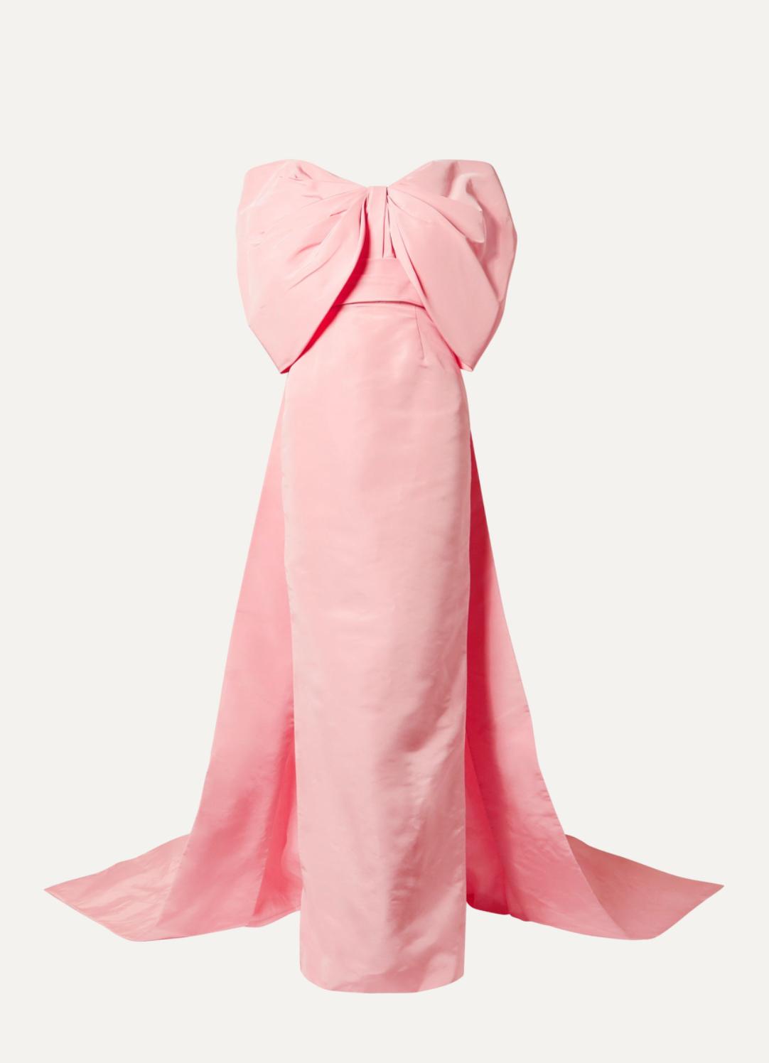 Pink off-the-shoulder satin gown featuring a dramatic oversized bow, ruched bodice, and a floor-length trumpet train.