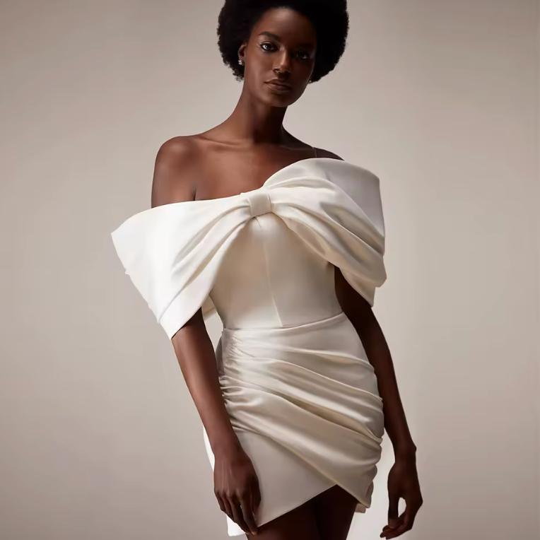 White satin off-the-shoulder mini dress featuring a ruched bodice and draped skirt design.