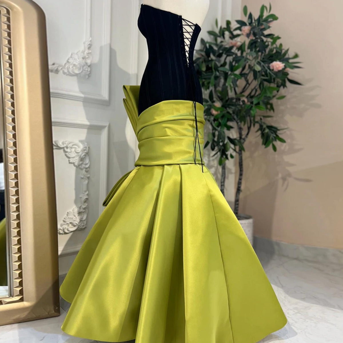 Black corset bustier mermaid gown with a lime green satin skirt and statement bow detail.