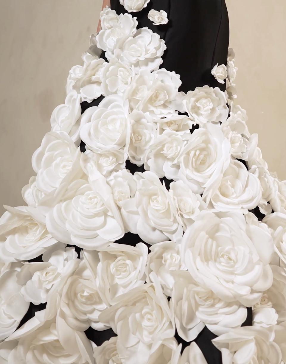 Black satin mermaid gown adorned with cascading white floral appliqués and shimmering sequins.