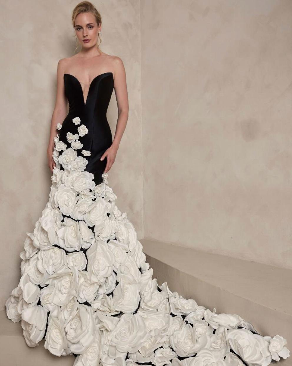 Black strapless satin mermaid gown with a deep V-neck and cascading white floral appliqués on a floor-length train.