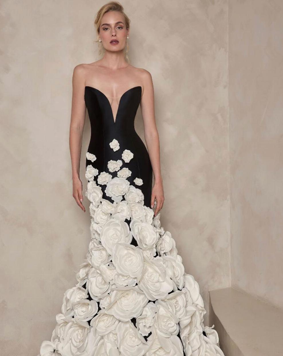 Black strapless mermaid gown with a deep V-neck and cascading white floral appliqués on satin fabric.