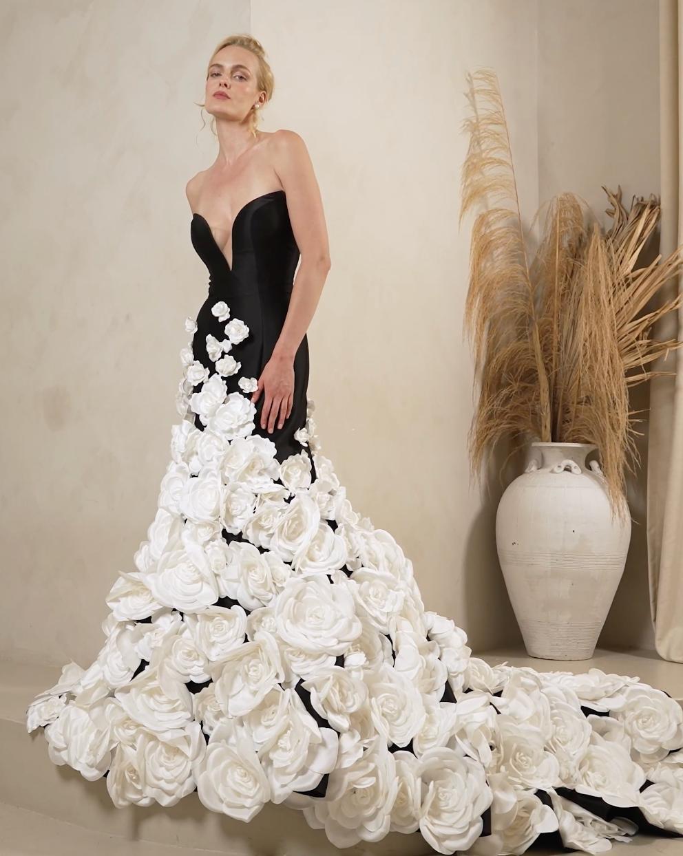 Black strapless satin mermaid gown with a deep V-neck and cascading white floral appliqués on the skirt.