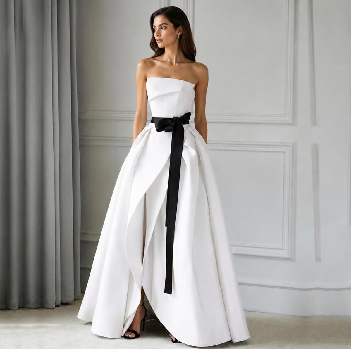 Strapless white satin twill A-line gown with strategic ruching and a dramatic black waist sash.