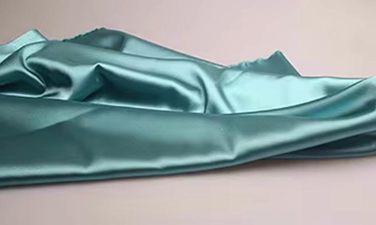Luxurious teal satin fabric draped in soft folds for the Dante two-piece suit set.
