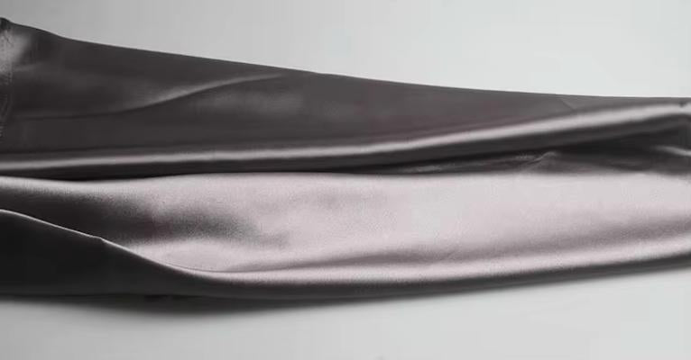 Close-up of smooth, charcoal grey satin fabric from the Dante two-piece suit set with a soft, reflective sheen.