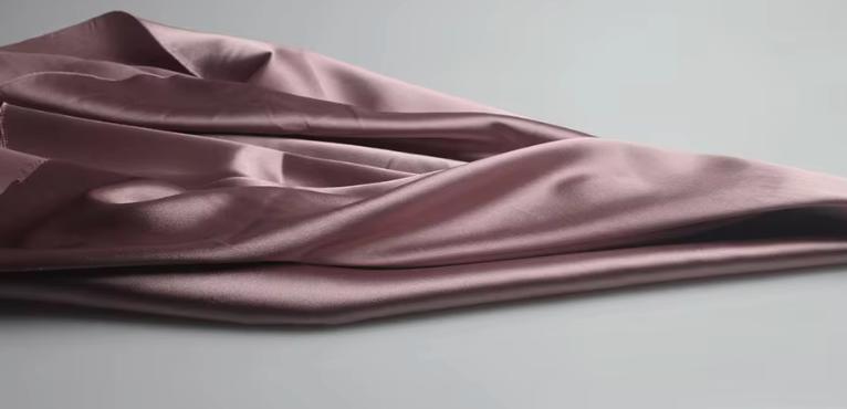 Close-up of luxurious, mauve-toned satin fabric draped in soft, elegant folds for the Dante two-piece suit set.