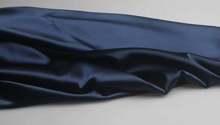 Close-up of luxurious navy blue satin fabric with soft, elegant folds for the Dante two-piece suit set.