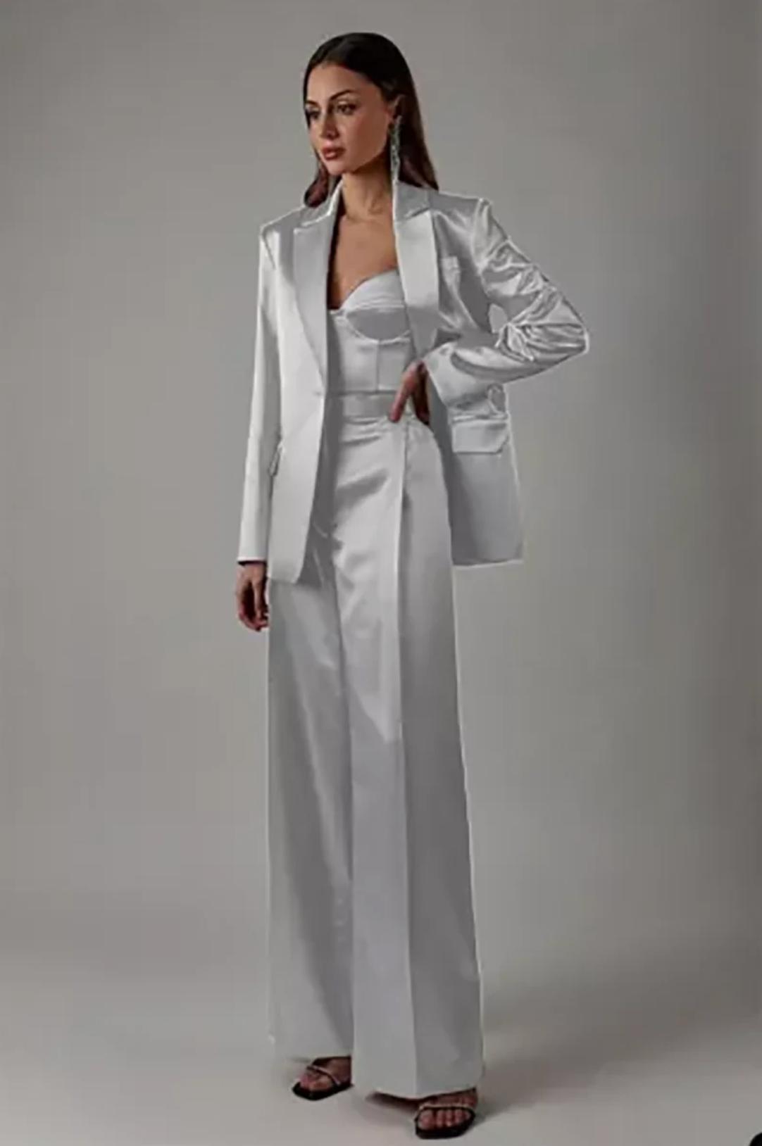 Elegant white satin two-piece suit with a sharp blazer, corset-style top, and high-waisted wide-leg trousers.