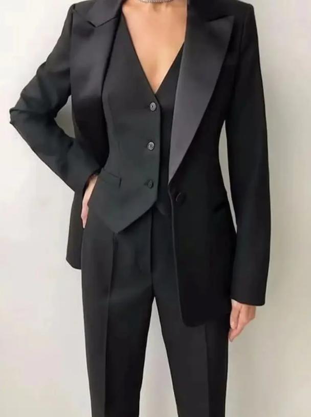 Women's black three-piece suit featuring a single-breasted blazer with satin lapels, tailored vest, and matching trousers.