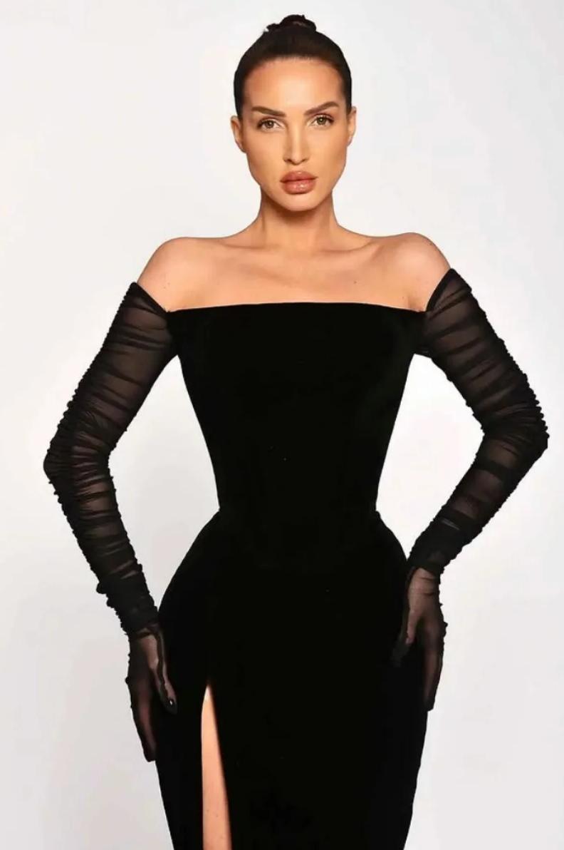 Black off-shoulder satin gown with long ruched sleeves and a high leg slit for a sophisticated evening look.