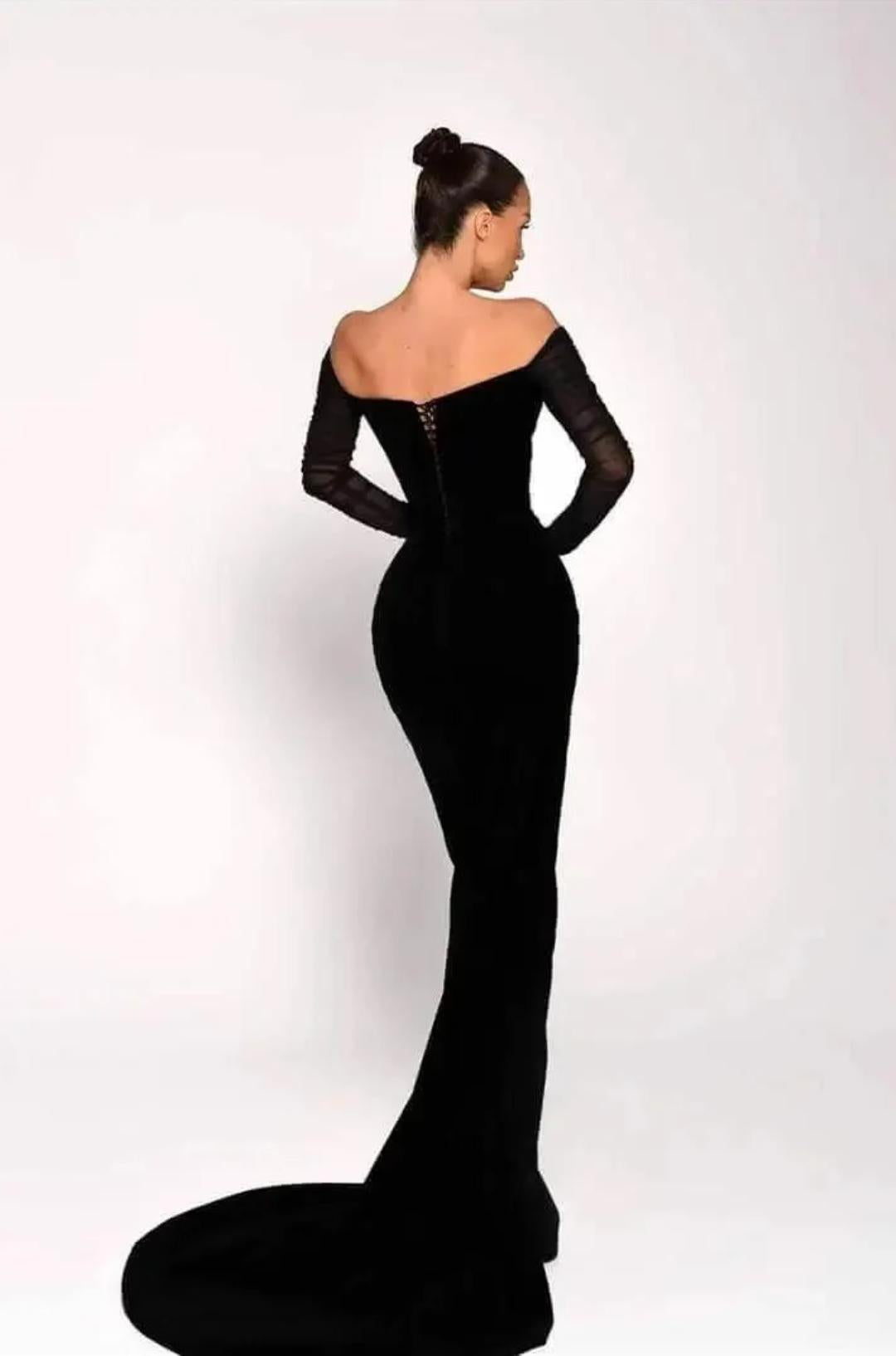 Black off-shoulder floor-length gown with long sheer sleeves and a lace-up back detail on a model.