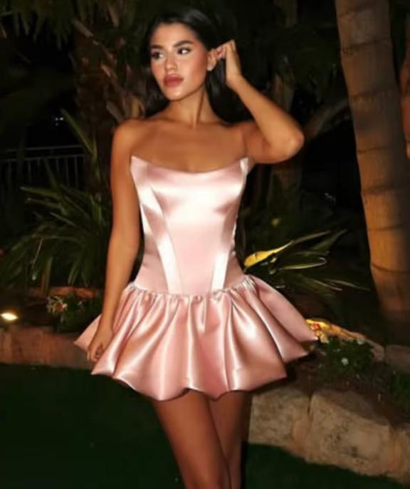 Model wearing a strapless pink satin mini cocktail dress with a structured bodice and ruffled A-line skirt.
