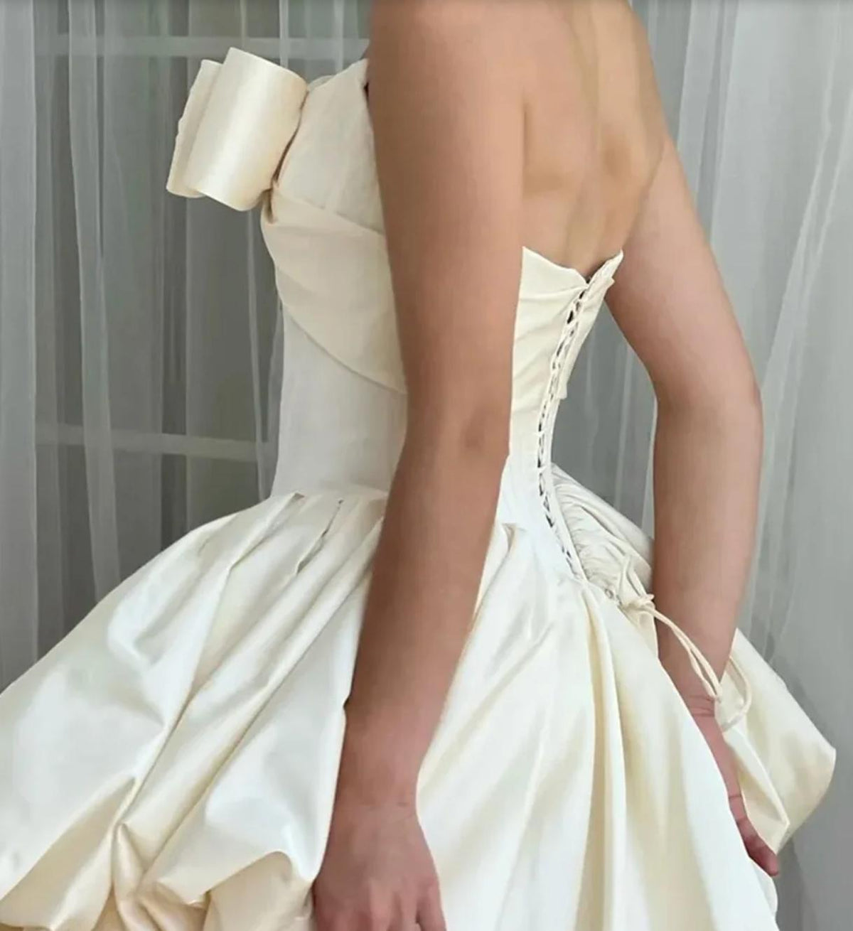 Strapless ivory satin mini dress with a bow detail and lace-up back closure.