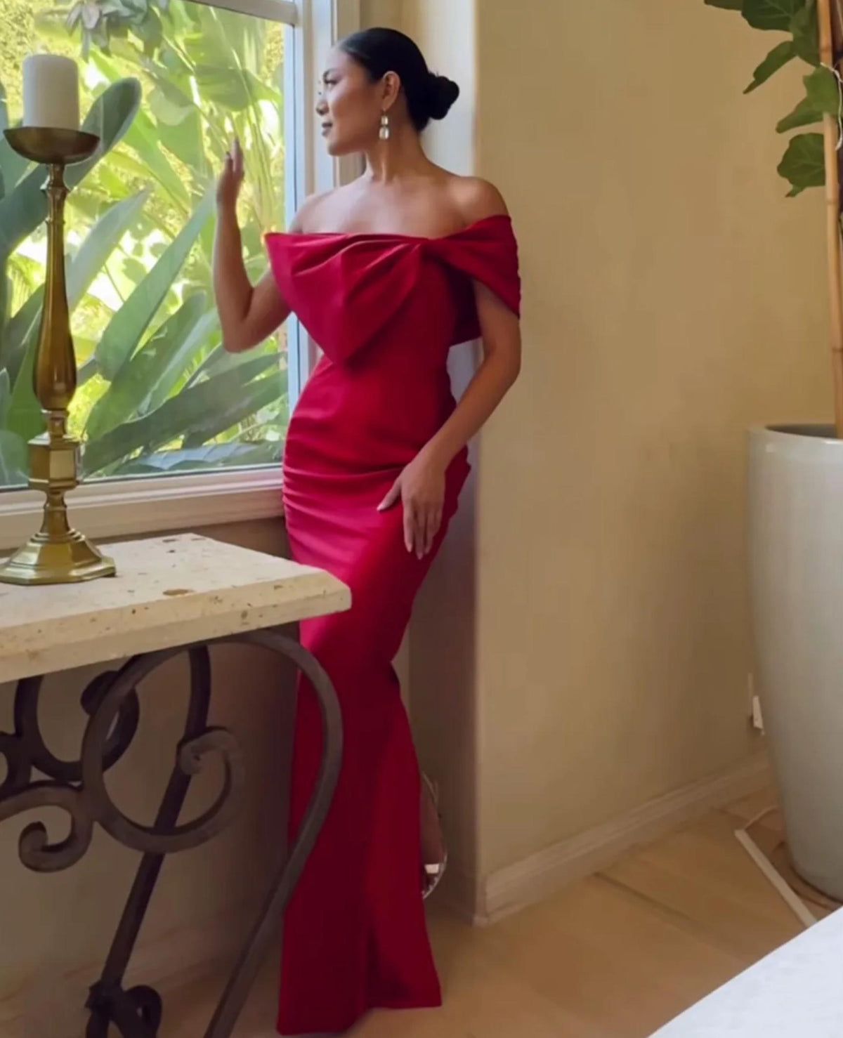Red satin floor-length evening gown with an off-shoulder bow detail and trumpet silhouette.