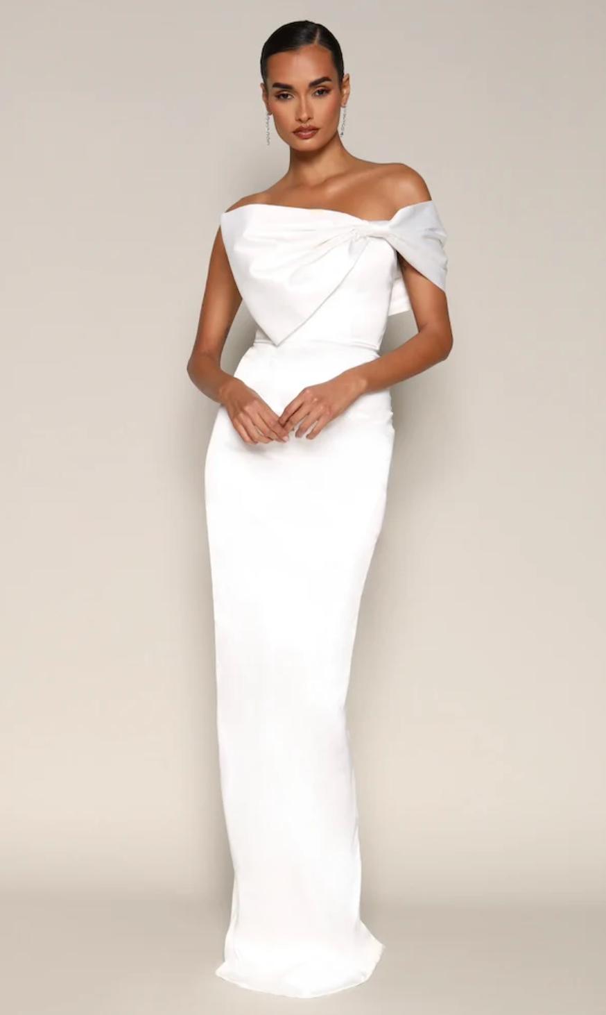 White satin evening gown featuring an off-shoulder neckline, oversized bow detail, and a sleek floor-length mermaid silhouette.