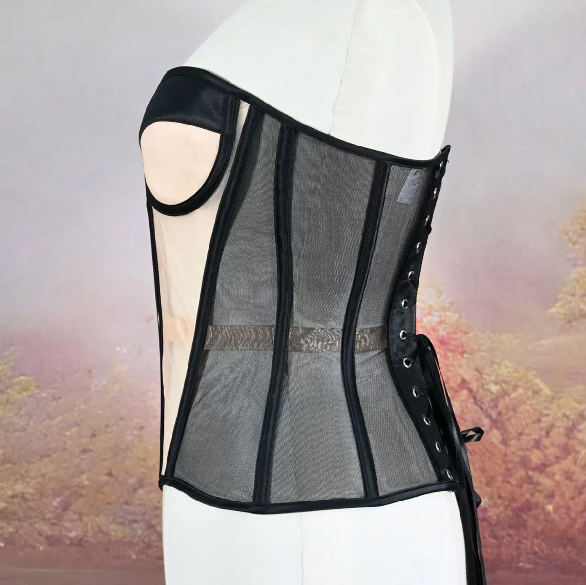 Black strapless mesh corset with structured boning, cutout bust detail, and side lace-up closure on a mannequin.