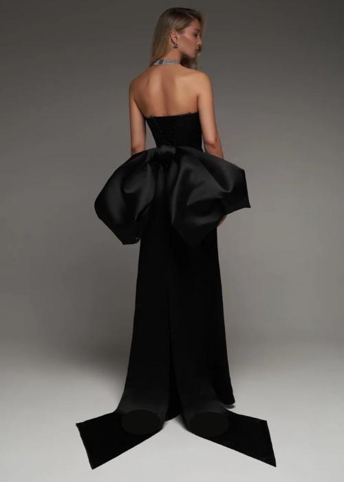 Backless black satin mermaid wedding dress with a sweetheart neckline and a dramatic oversized bow detail.