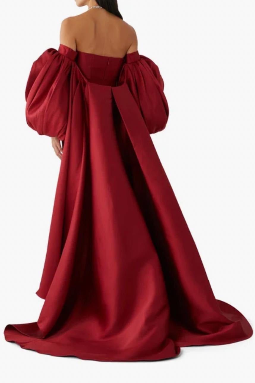 Red strapless evening gown in Mikado satin with a full-length skirt and detachable dramatic puff sleeve cape.