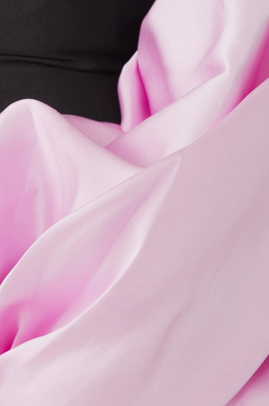 Close-up of a luxurious pink Mikado satin evening gown fabric with soft, elegant folds against a black bodice.