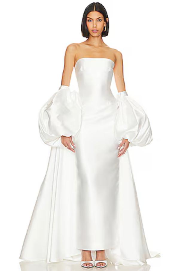 White strapless Mikado satin evening gown with a fitted bodice and dramatic removable puff sleeve cape.