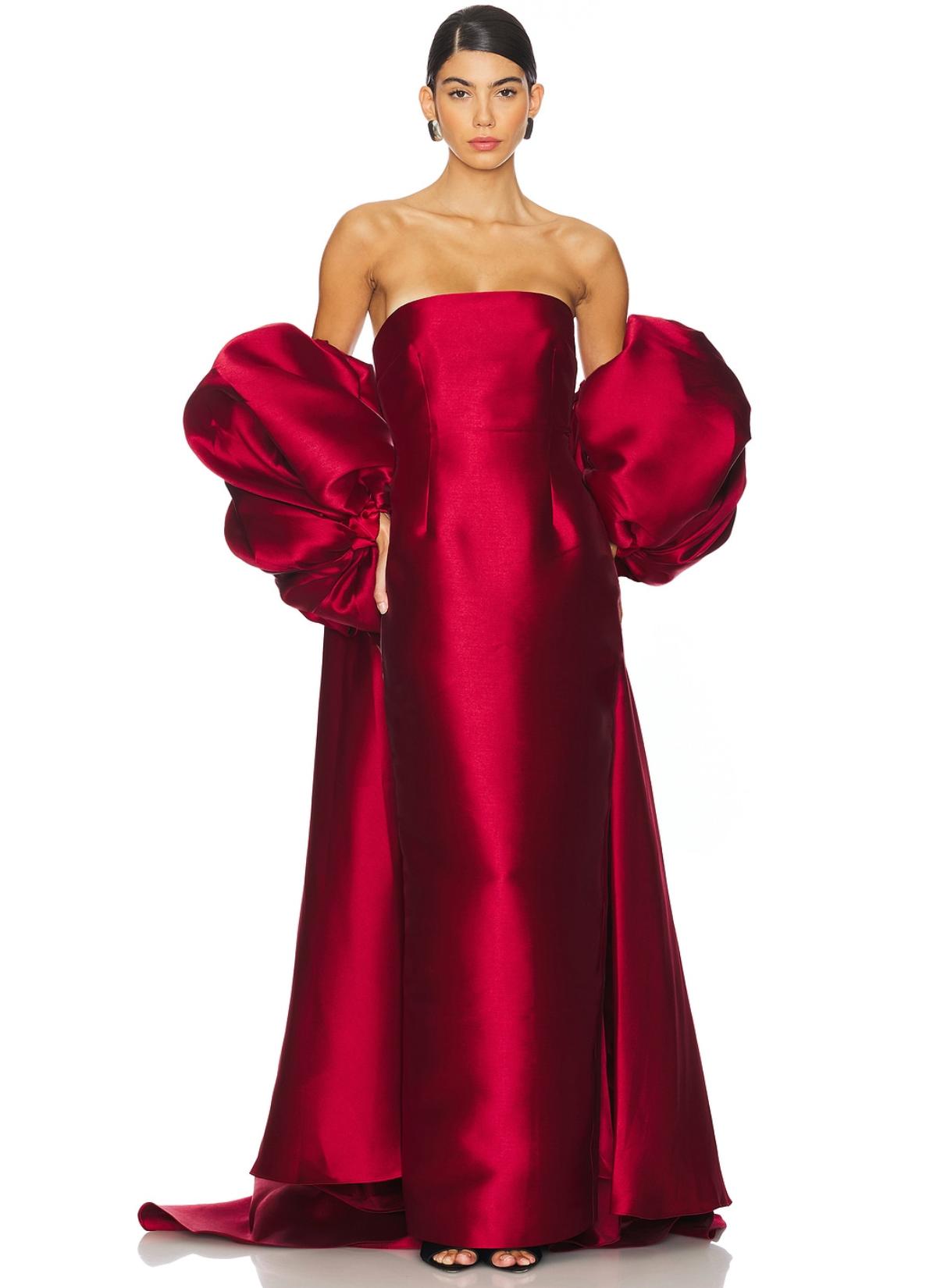 Strapless red satin evening gown featuring a structured bodice and dramatic, voluminous removable puff sleeve cape.