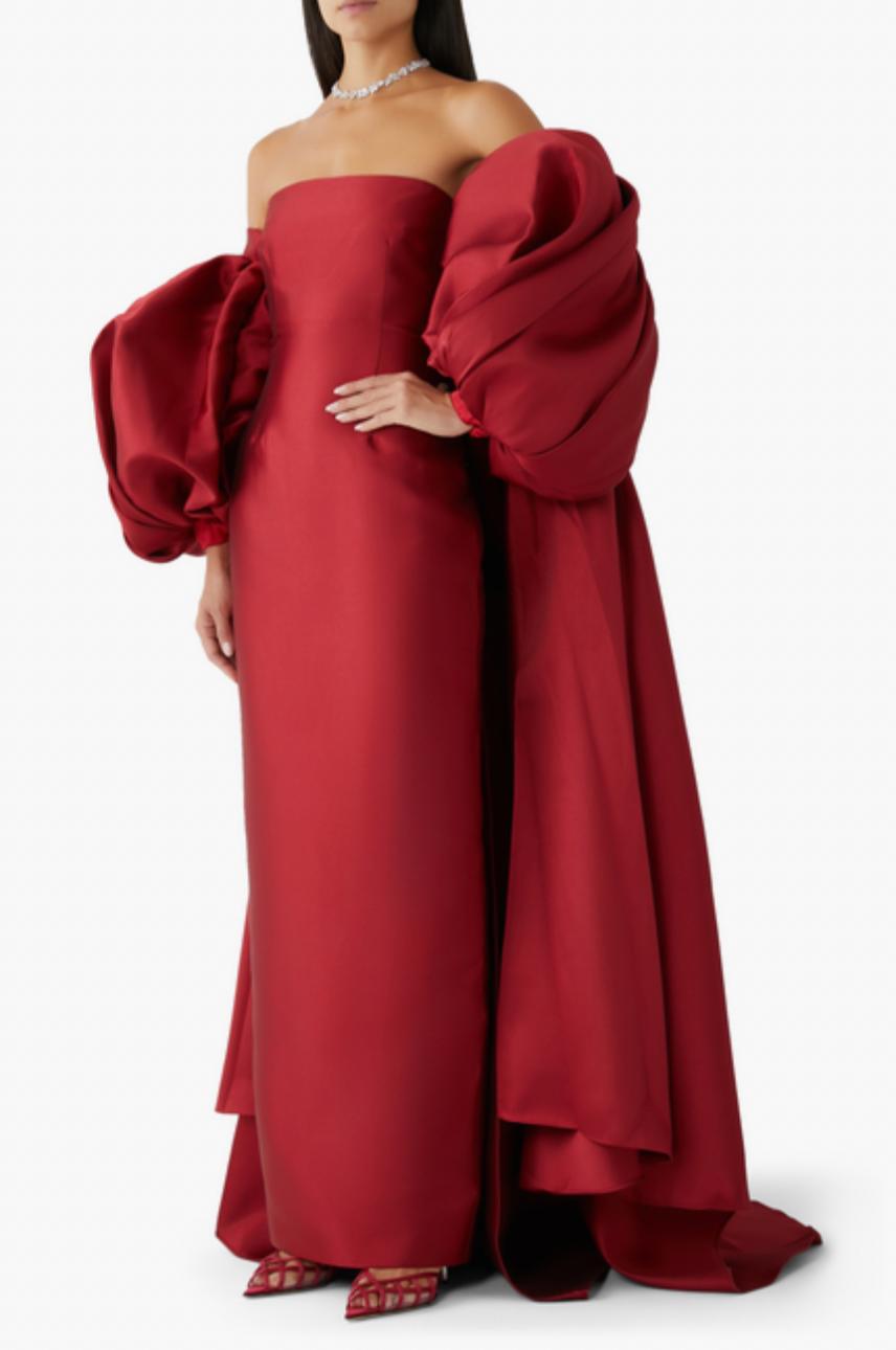 Red strapless Mikado satin evening gown featuring a fitted bodice and dramatic, removable puff sleeve cape.