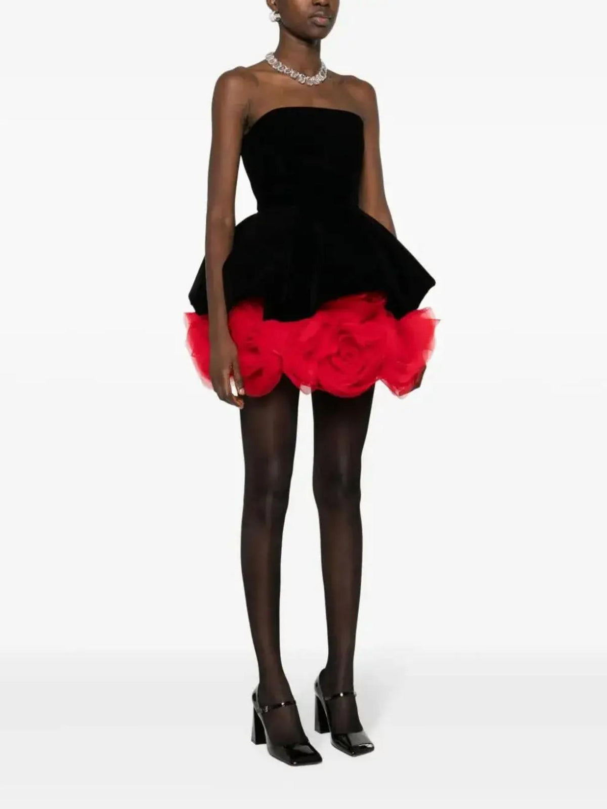 Strapless black velvet mini dress featuring a voluminous red tulle skirt with floral accents and a sweetheart neckline.