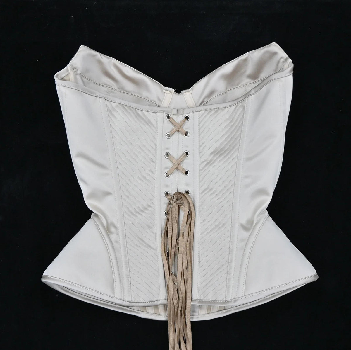 Cream-colored luxury corset bustier with structured boning, diagonal stitching, and a classic lace-up front closure.