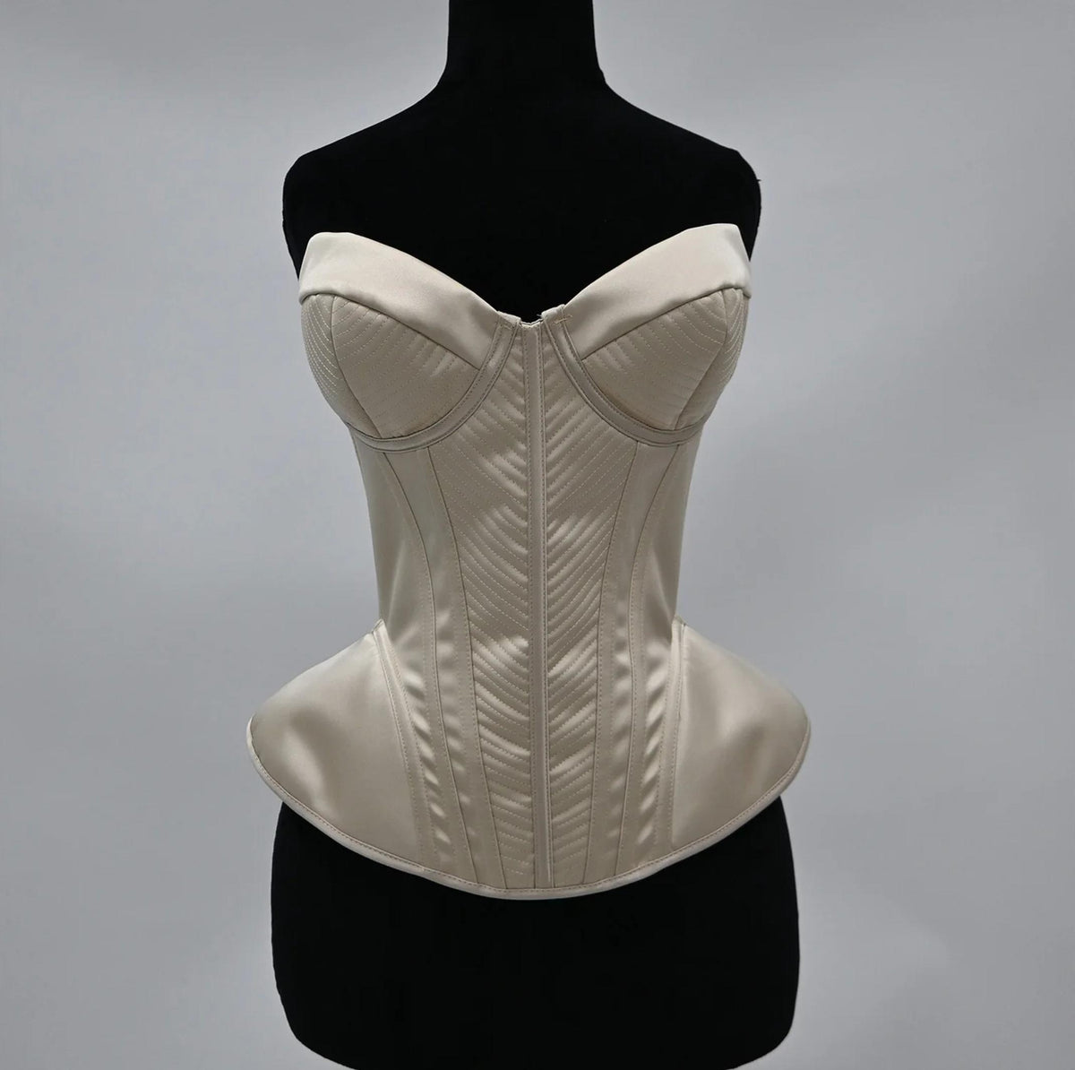 Cream-colored satin corset bustier with structured boning, sweetheart neckline, and elegant quilted chevron detailing.