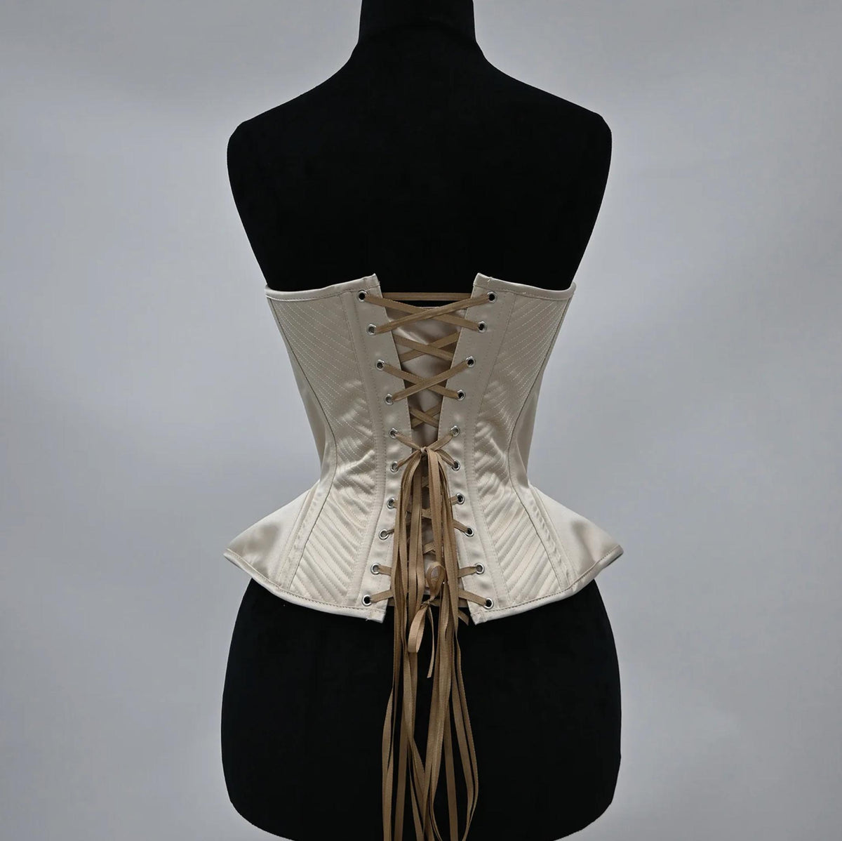 Cream-colored handmade corset bustier with structured boning, intricate stitching, and a classic lace-up back closure.