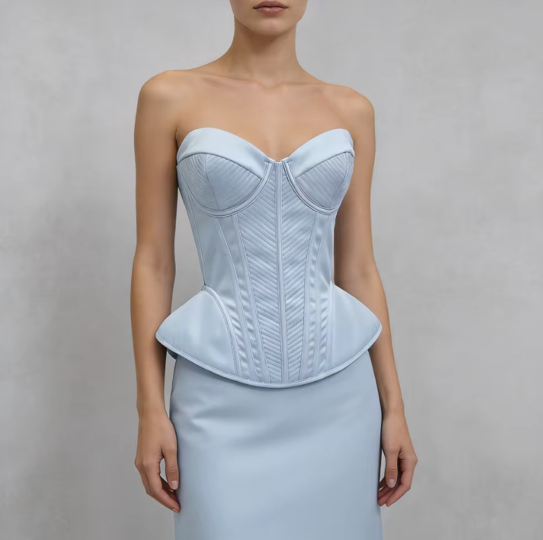 Light blue structured corset bustier with quilted paneling and a peplum waist, worn over a matching skirt.