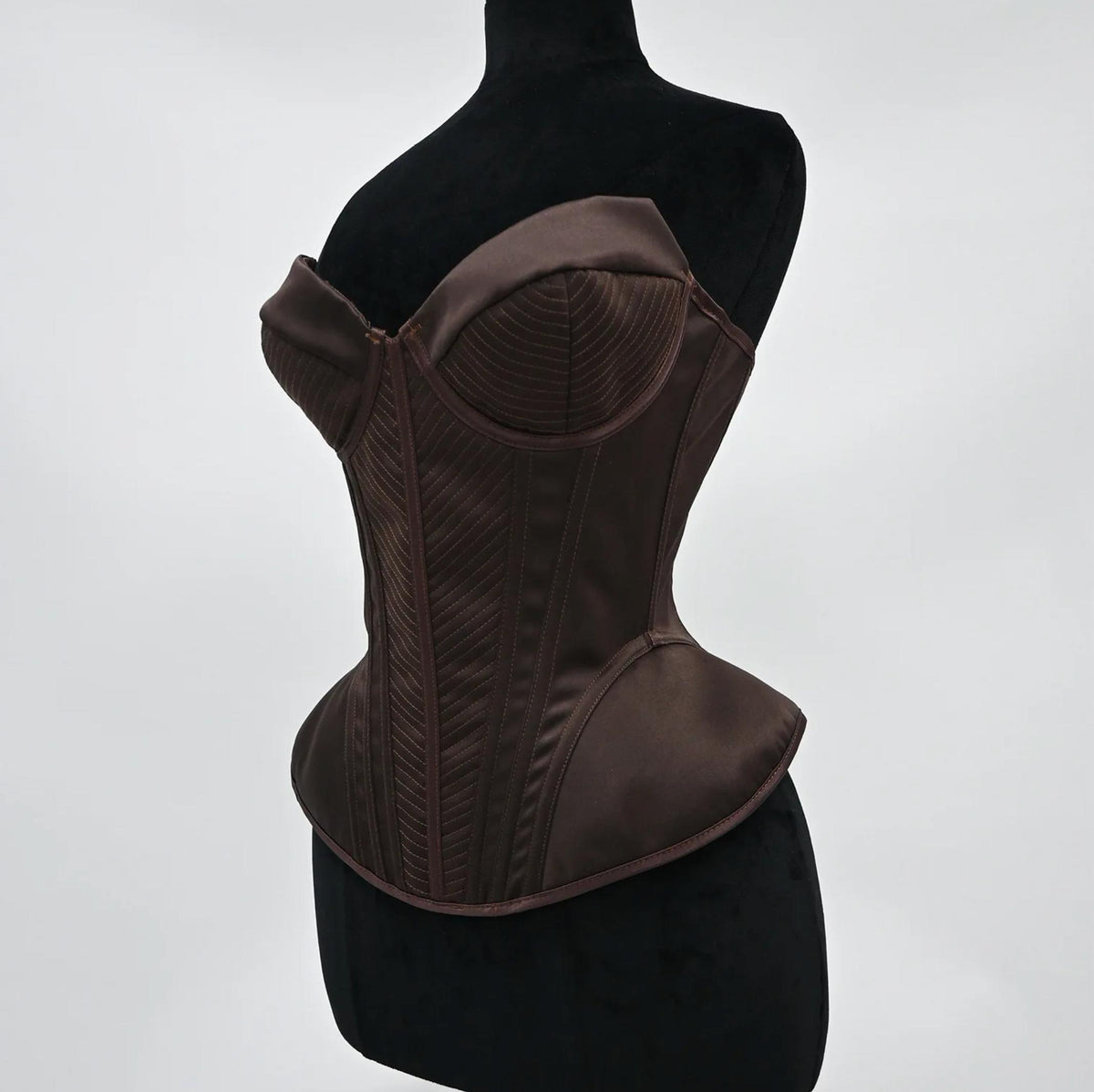 Structured dark brown satin corset bustier with intricate stitched paneling and a sculpted, vintage-inspired silhouette.
