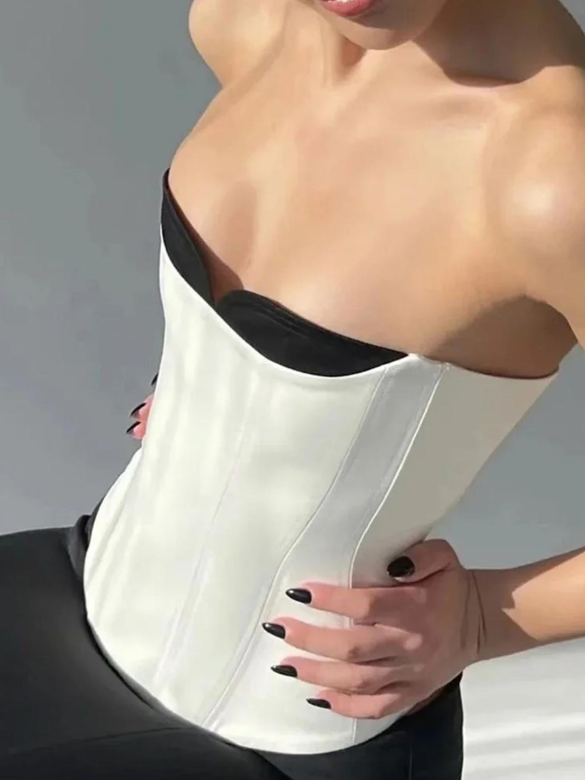 Structured white crepe corset top with a boned bodice and contrasting black neckline inserts.