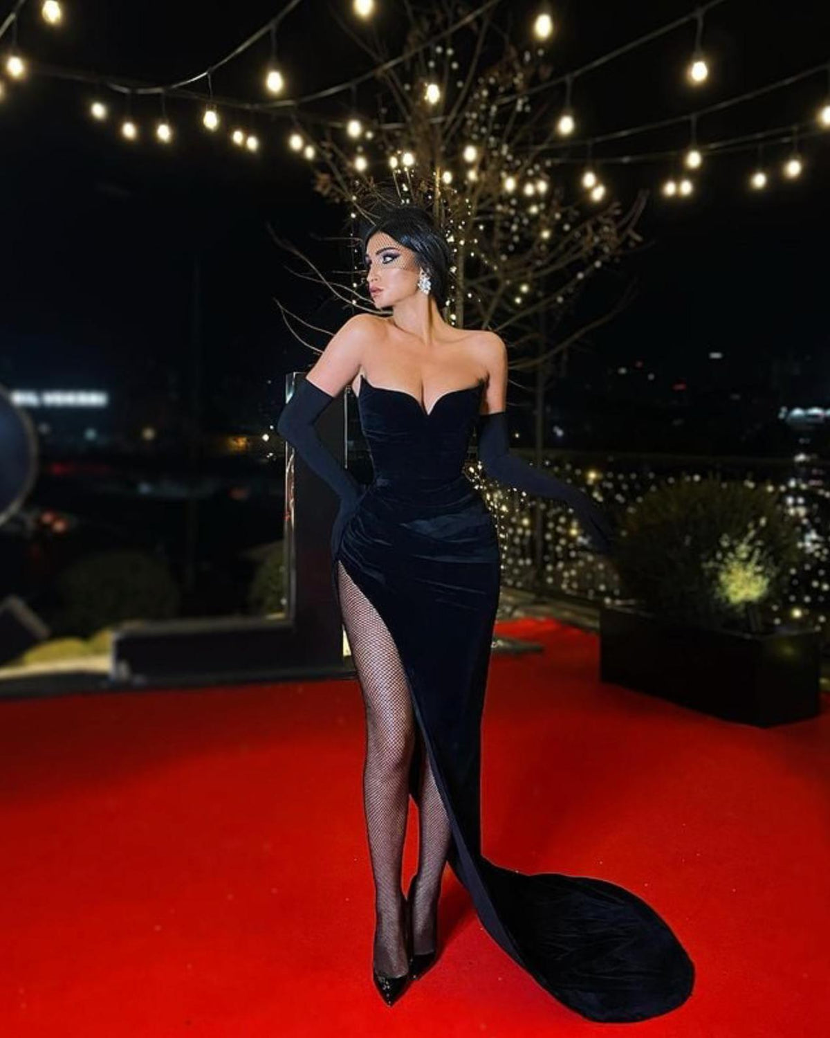 Black velvet strapless sweetheart gown with a high side slit, worn with matching opera gloves on a red carpet.