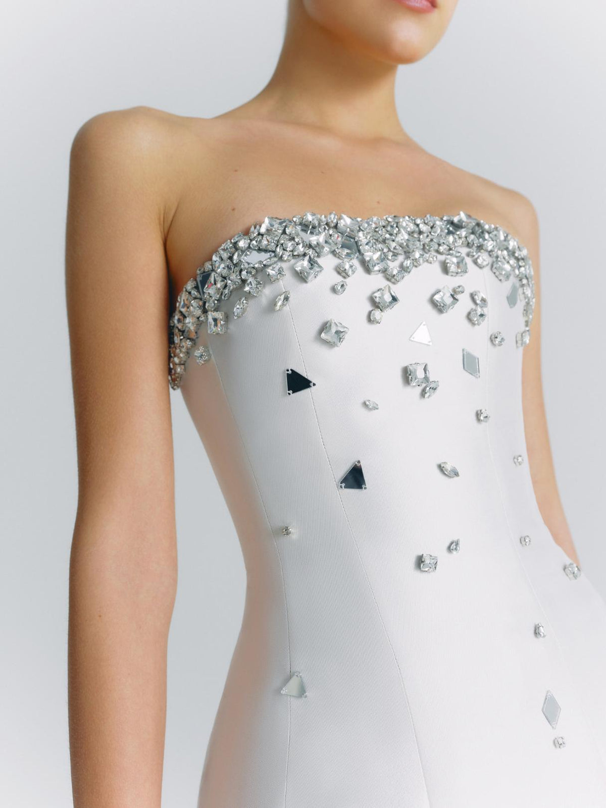White strapless satin mini dress featuring a crystal-embellished bodice with scattered geometric mirror accents.