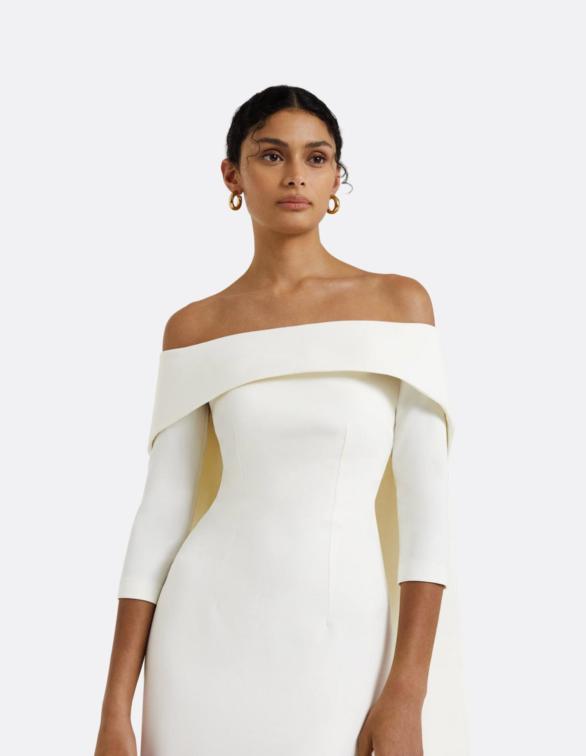 Elegant white off-the-shoulder floor-length gown in smooth jersey with a fitted silhouette and three-quarter sleeves.