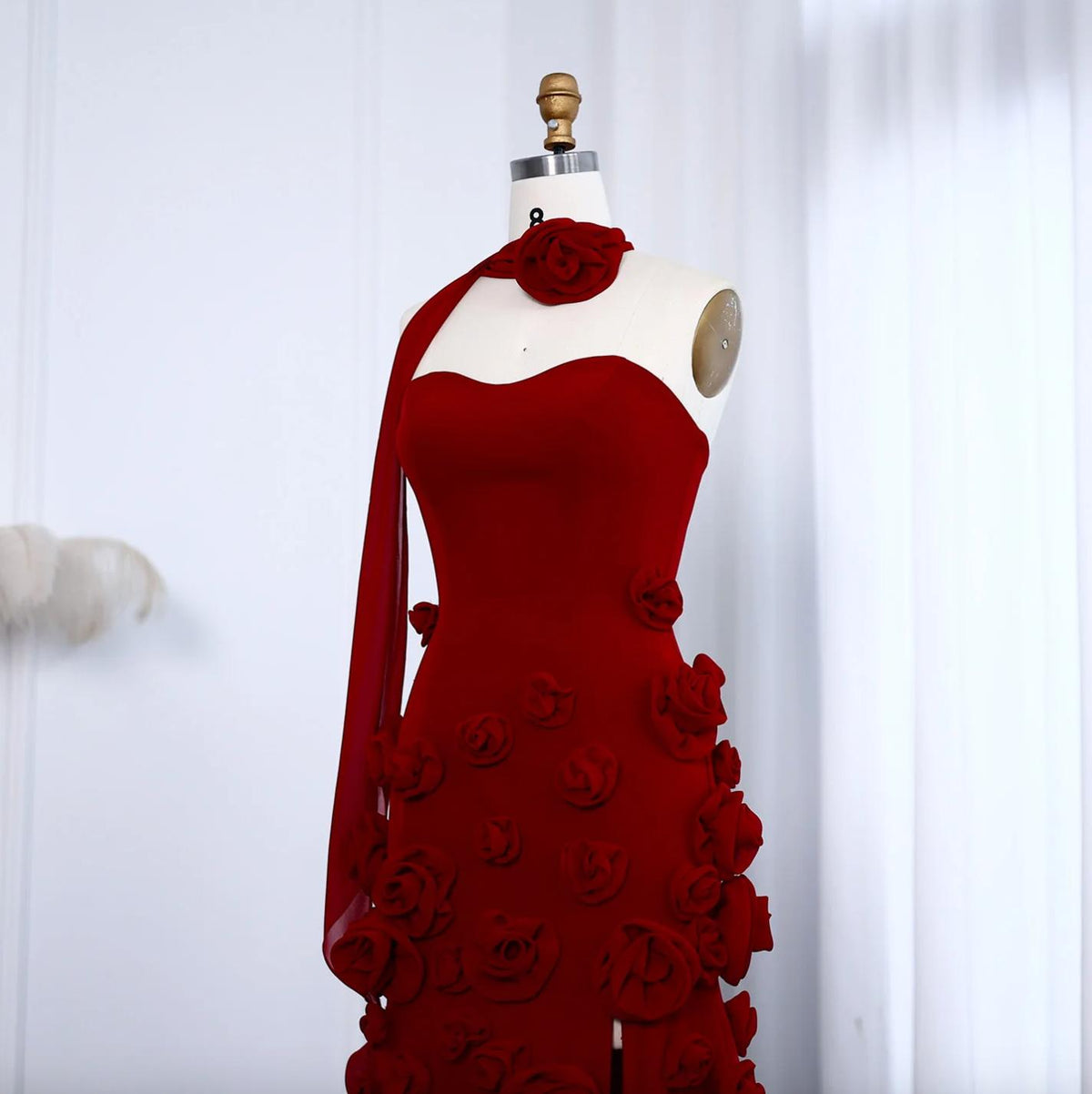 Red Evelyn Walk gown featuring a sweetheart neckline, 3D floral appliqués, and a flowing tulle sash on a mannequin.