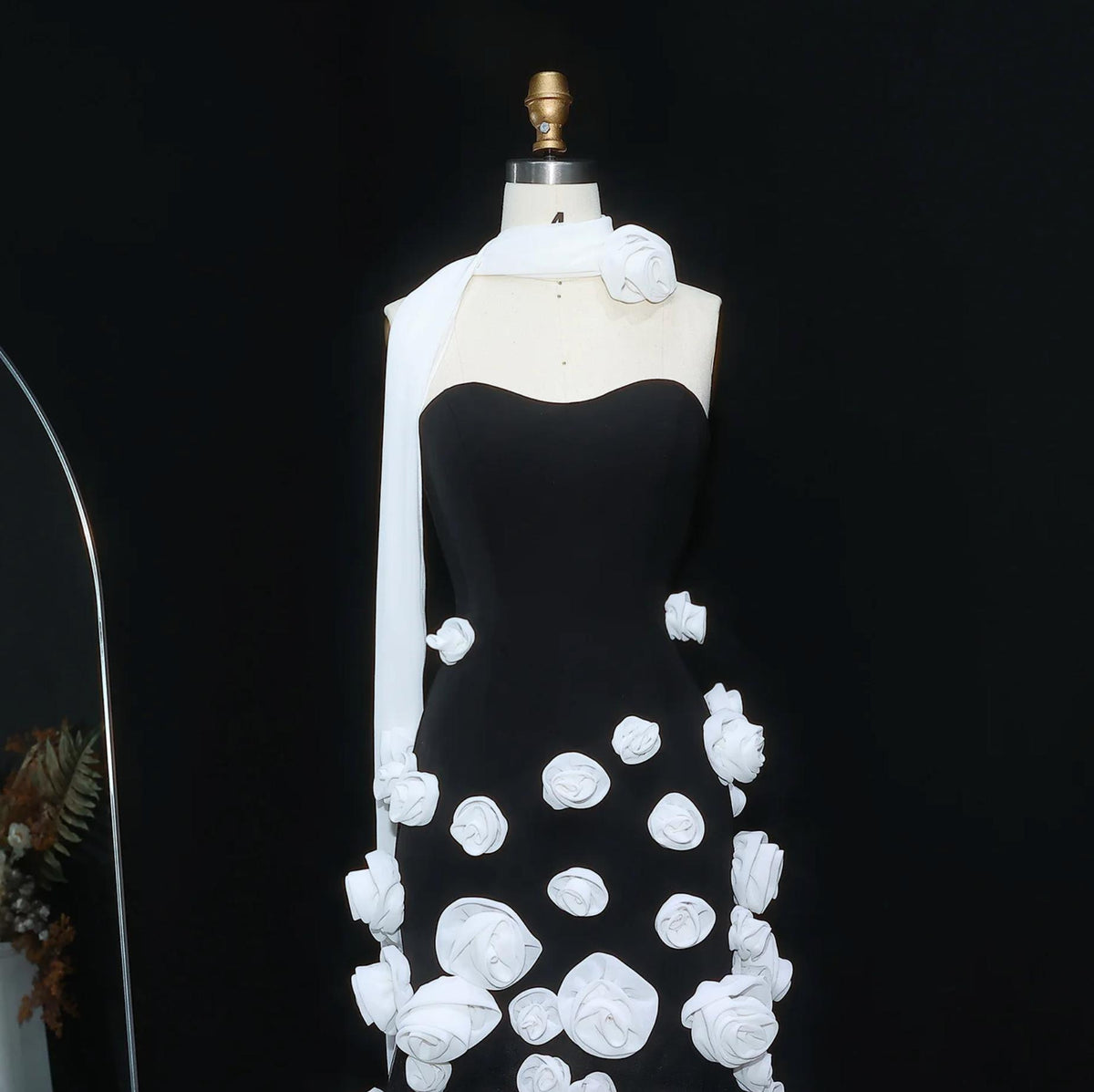 Black trumpet gown with a sweetheart neckline and white 3D floral appliqués on a mannequin.